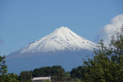 Low angle view of snowcapped mountains against clear blue sky
