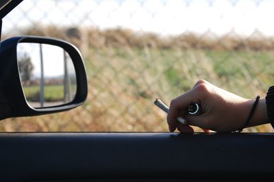 Close-up of hand holding side-view mirror