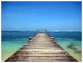 Empty pier over sea against blue sky