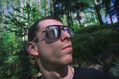 Close-up of young man wearing sunglasses at forest