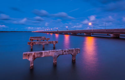 Bridge over calm sea against sky