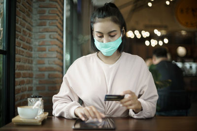 Young woman using tablet on table at window