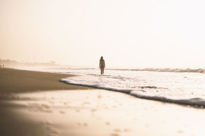 Man walking on beach against clear sky