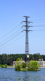 Electricity pylon by trees against sky