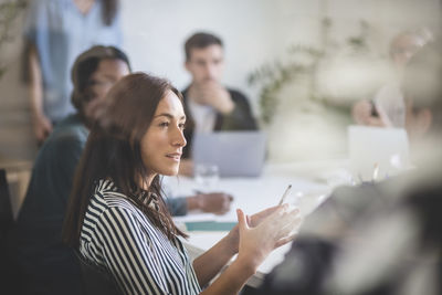 Businesswoman explaining colleagues during brainstorming session in creative office