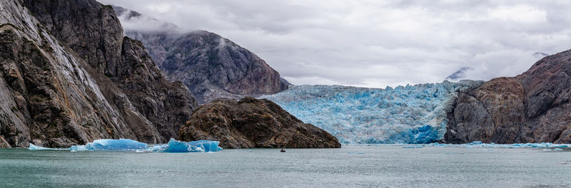 Panoramic shot of rocks by sea against sky