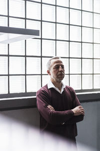 Mature man leaning against glass brick wall with eyes closed