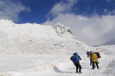 People on snowcapped mountain against sky