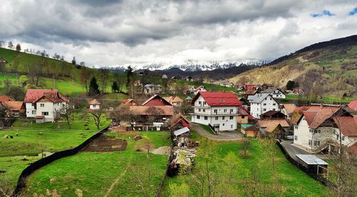 Houses on field against cloudy sky