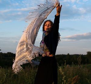 Young woman looking away while standing on field against sky