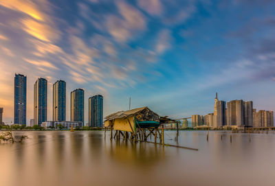 Panoramic view of sea and buildings against sky during sunset