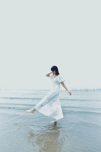 Full length of woman standing on beach against clear sky