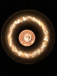 Close-up of illuminated light bulb over black background