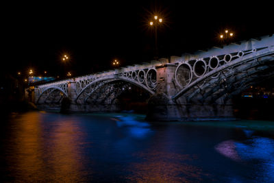 Arch bridge over river at night