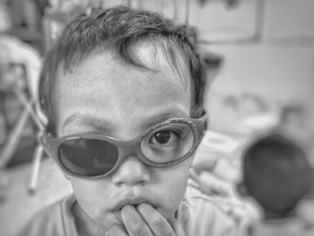 Close-up portrait of boy wearing broken sunglasses at home