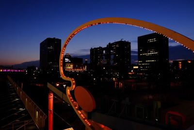 Illuminated bridge against blue sky at night