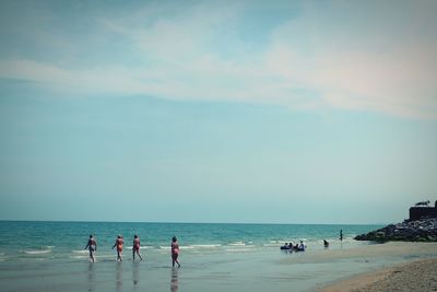 People enjoying at beach against sky