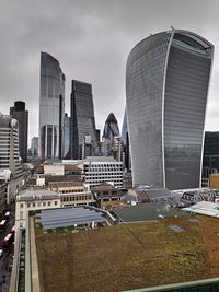 Modern buildings in city against cloudy sky