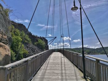 Footbridge over mountain against sky