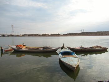 Boats moored on river against sky