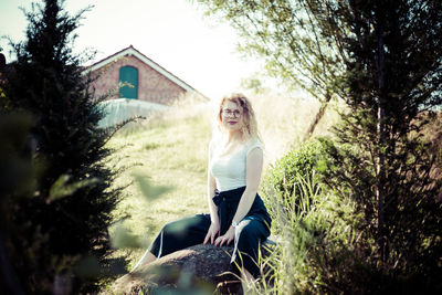 Portrait of woman sitting on land against trees