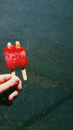 Cropped image of hand holding ice candy against street