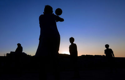 Silhouette people against clear sky during sunset