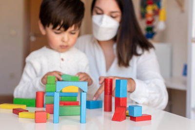 Mother assisting son in puzzle sitting at home