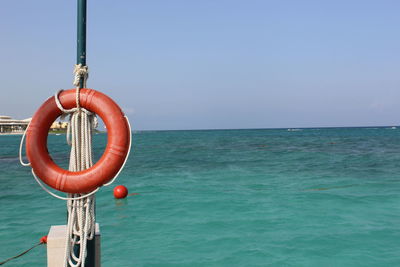 Rubber ring on pole against calm blue sea