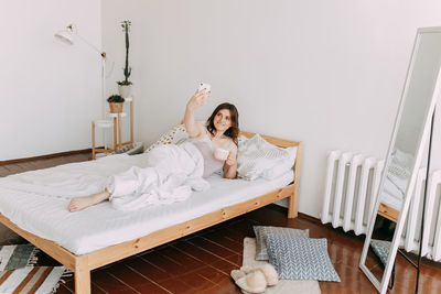 Beautiful girl talking on the phone using technology while lying in bed at home