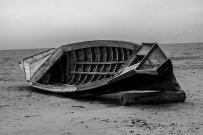 Abandoned boat on beach against sky