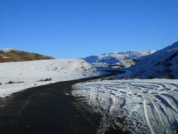 Scenic view of snowcapped mountains against clear blue sky