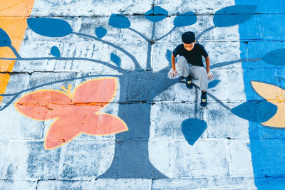 Full length of boy sitting on colorful footpath