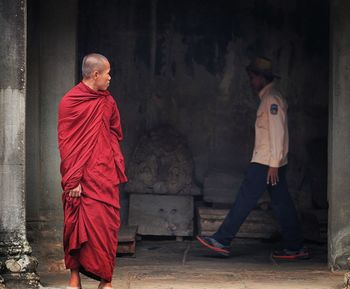 Monk looking at man walking in angkor wat