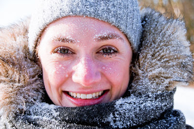 Close-up portrait of young woman in warm clothing with snow