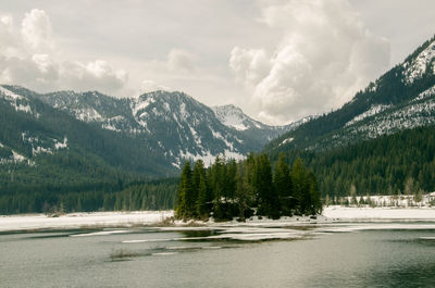 Scenic view of river and mountains against cloudy sky