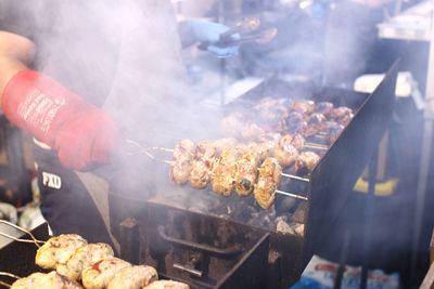 Midsection of man by meat on barbecue grill