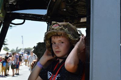 Portrait of boy wearing army helmet in vehicle