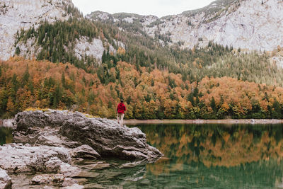 Rear view of man standing on rock by lake