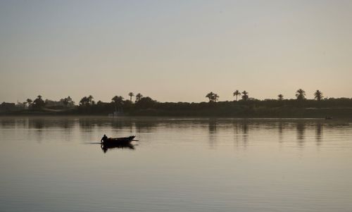 Silhouette man in lake against clear sky