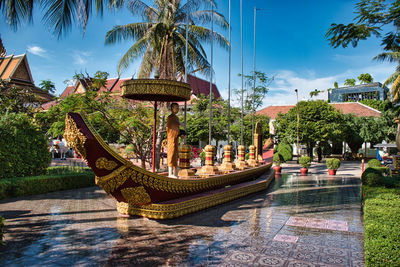 Statue by palm trees against sky