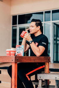 Full length of young man sitting at table