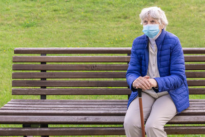 Senior woman wearing mask sitting outdoors