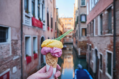 Hand holding ice cream and canal in venice, italy. summer vacation 