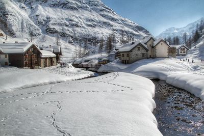 Snow covered houses by buildings against mountains