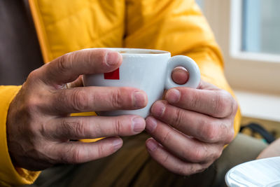 Midsection of man holding coffee cup