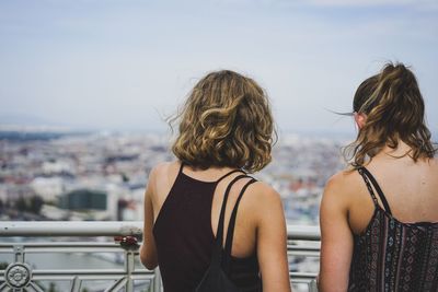 Rear view of woman looking at cityscape against sky