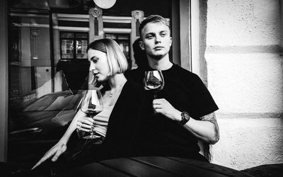 Portrait of young couple sitting on wall