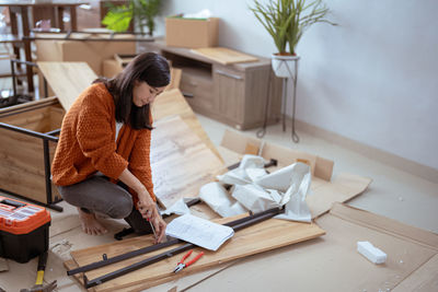 Woman assembling furniture at home