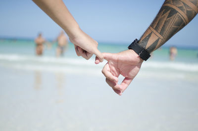 Low angle view of hands holding water against sea